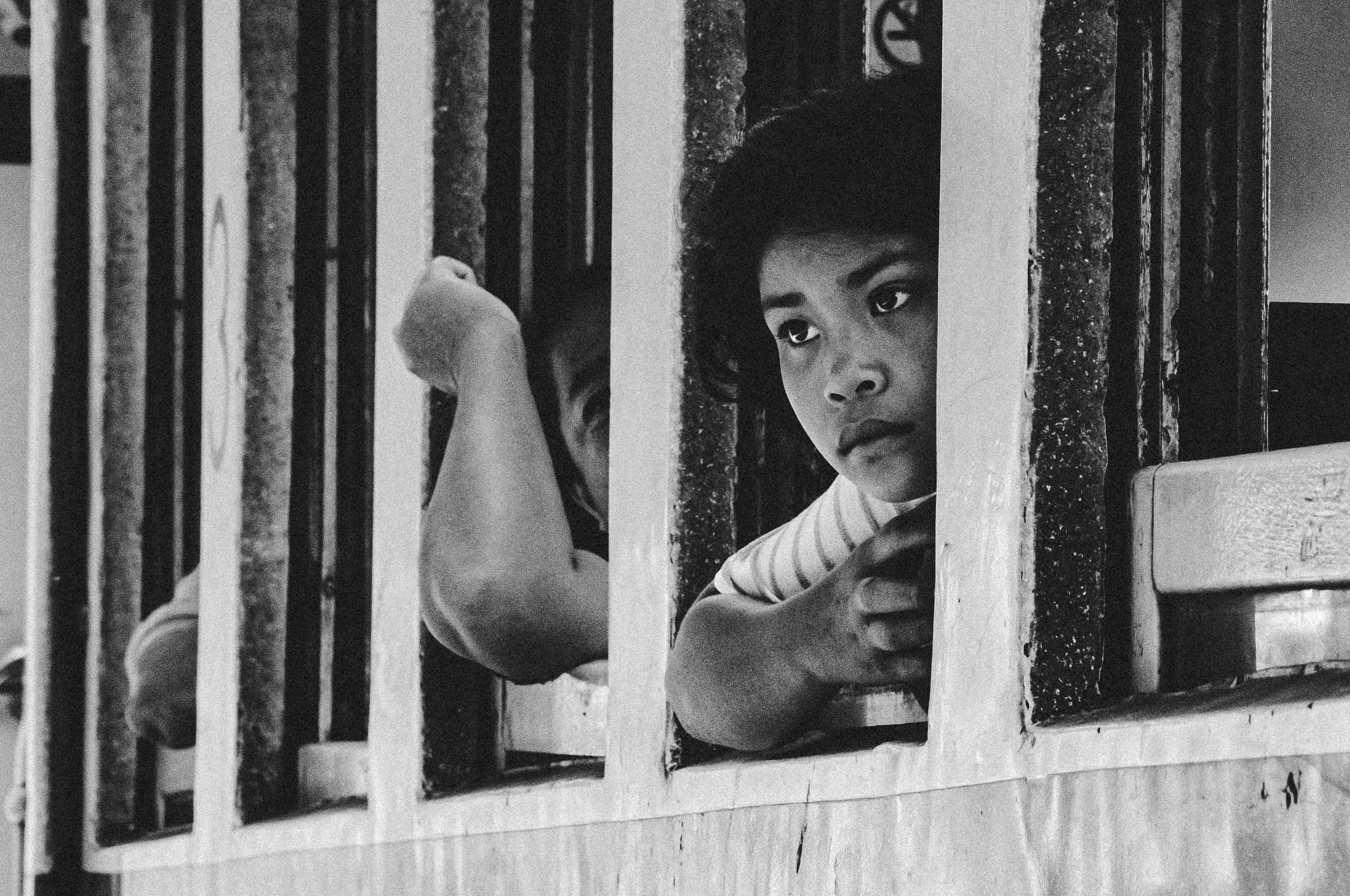 Boy looking through train window bars